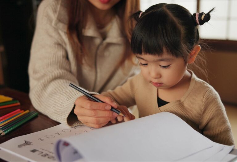 Mother, child and drawing learning or pencil for home schooling lesson, Japanese or tutor. Female person, girl daughter and book paper in Tokyo or writing help for art studying, creative or project Mother, child and drawing learning or pencil for home schooling lesson, Japanese or tutor. Female person, girl daughter and book paper in Tokyo or writing help for art studying, creative or project.